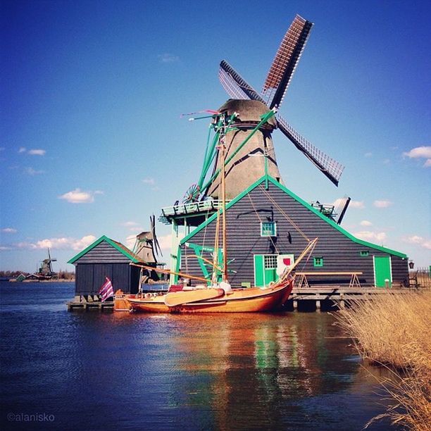 nautical vessel, mode of transport, transportation, water, boat, sky, windmill, traditional windmill, waterfront, alternative energy, moored, wind power, wind turbine, environmental conservation, renewable energy, ship, blue, mast, outdoors, travel