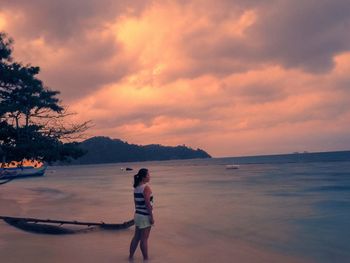 Full length of silhouette boy standing on beach against sky during sunset