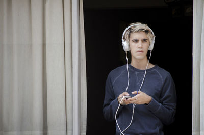 Portrait of young man standing against wall