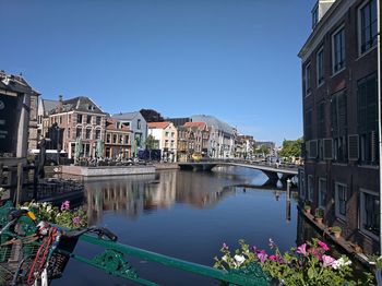 Canal amidst buildings in city against clear sky