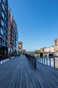 Footpath by river against buildings in city