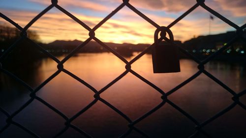 Close-up of chainlink fence against sunset sky