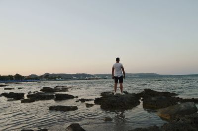 Rear view of man looking at sea against sky