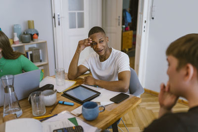 Smiling man looking at friend while studying together