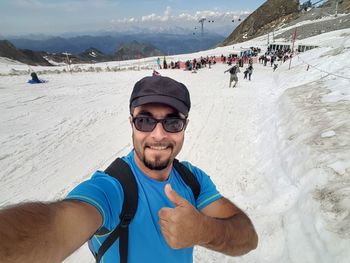 Smiling man taking selfie while standing on snowy field