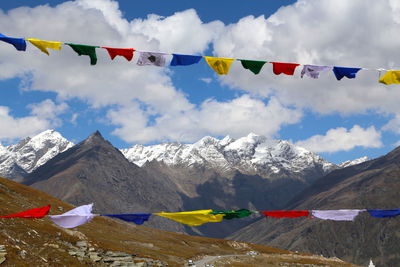 Multi colored flags on mountain against sky