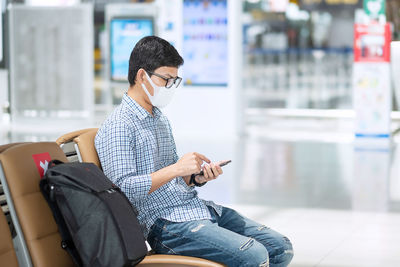 Man with mask using mobile phone in airport