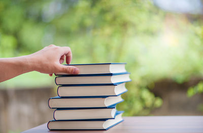 Hand holding book on stack of table