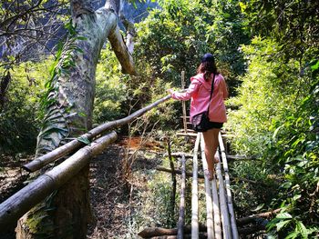 Woman standing by tree in forest