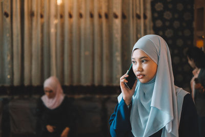 Young woman wearing hijab talking on mobile phone