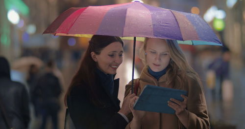 Portrait of happy woman holding umbrella standing in rain