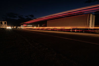 Light trails on road against sky at night