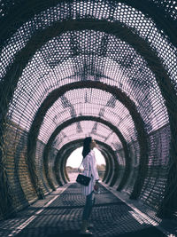 Rear view of woman standing in tunnel