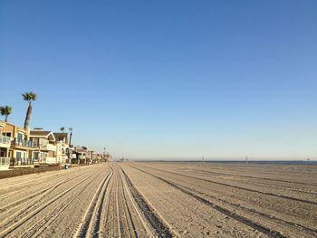 Tire tracks on beach against clear blue sky