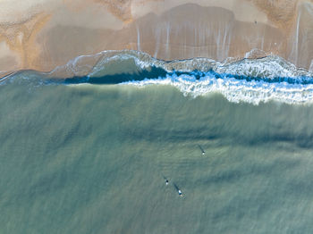 An aerial shot of surfers surfing waves at boscombe pier on the south coast of england