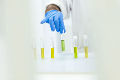 Close-up of hands arranging multi colored chemicals in test tubes in a row