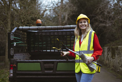 Happy worker with work tool standing by pickup truck