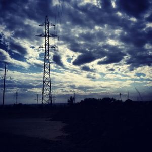 Low angle view of silhouette electricity pylon against sky