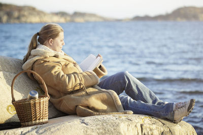 Woman reading book at sea