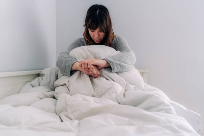 Young woman sitting on bed at home