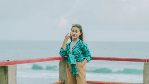 Woman standing by sea against sky