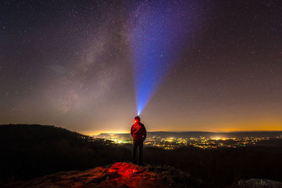 Man standing on illuminated street against star field at night