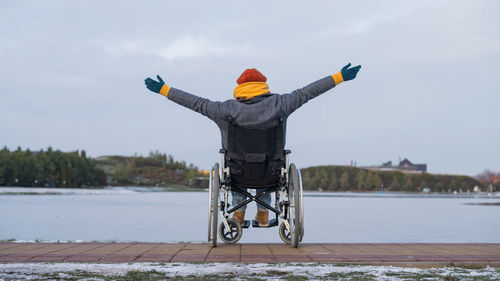 Rear view of woman standing by lake