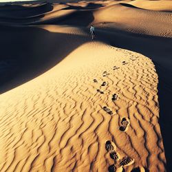 High angle view of man walking on sand dunes at desert