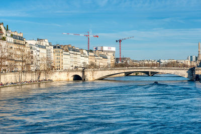 Arch bridge over river against buildings in city