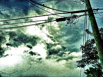 Low angle view of power lines against cloudy sky