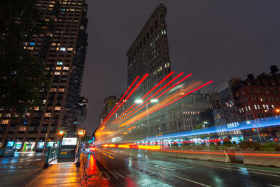 Illuminated city street and buildings against sky at night