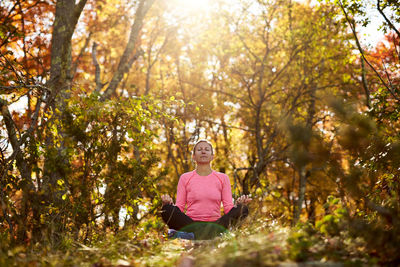 A woman meditates outdoors on a beautiful fall day.