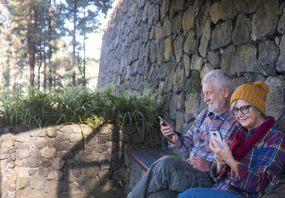 Senior couple using phones while sitting outdoors