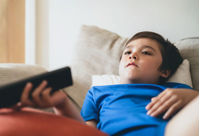 Boy  watching cartoon, school kid sitting on couch holding remote control and watching tv