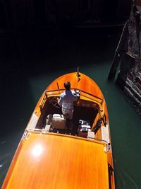 High angle view of man sitting on boat moored at sea