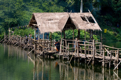 Wooden house by lake against trees and plants