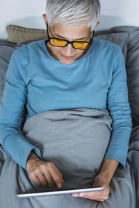 Midsection of man wearing hat sitting on bed at home