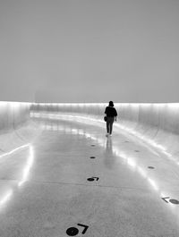 Rear view of man walking on road against clear sky