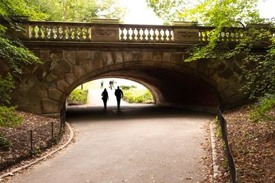 Rear view of people walking on bridge