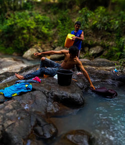 People sitting on rock in water