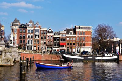 Sailboats moored on canal by buildings in city