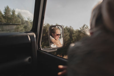 Reflection of woman seen in side-view mirror of car