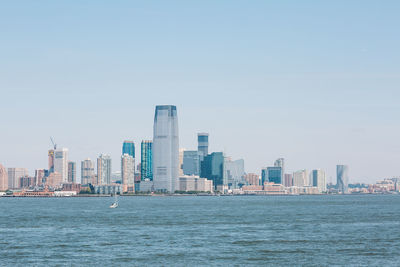 Sea and cityscape against clear sky