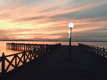 Pier over sea against sky during sunset