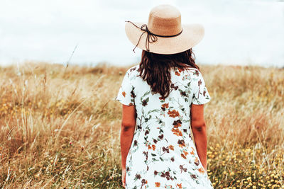 Rear view of woman standing on field against sky