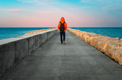 Person walking on pier at sunset