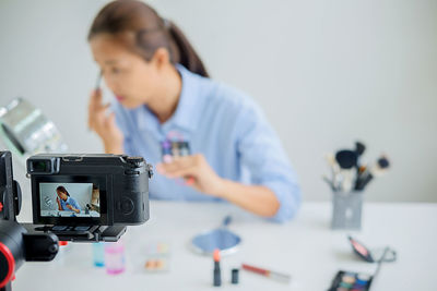 Close-up of camera capturing woman while doing make-up