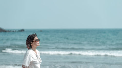 Woman standing on beach against sky