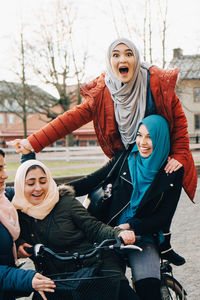 Cheerful multi-ethnic friends enjoying with bicycle in city