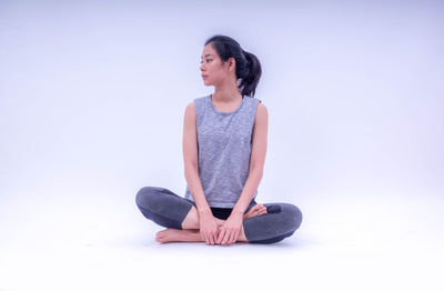 Full length of woman sitting against white background